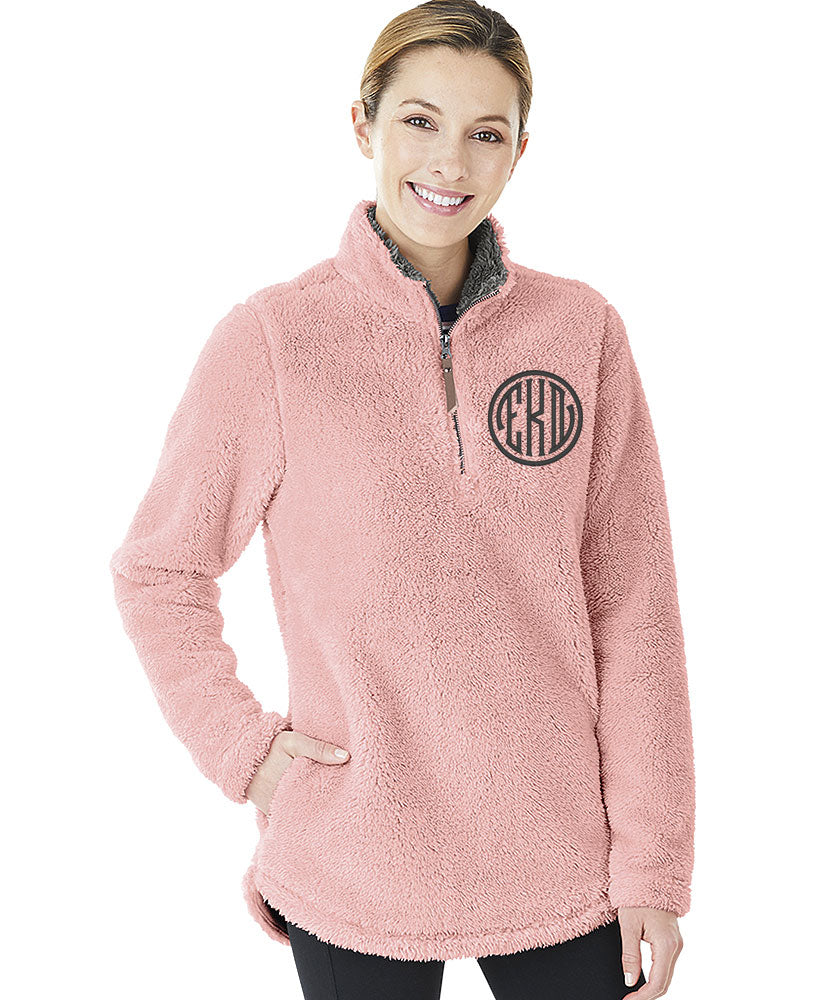 Woman wearing a pink Charles River Newport fleece pullover with a black circular monogram on the chest.