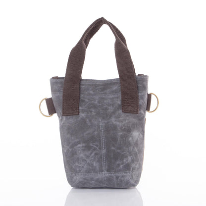 Gray waxed canvas wine bottle tote with brown fabric handles, brass ring details on sides, and visible seam stitching down front panel