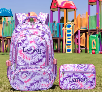 Pink and purple tie-dye backpack and lunchbox set, both embroidered with the name Laney.