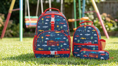 Three blue Stephen Joseph backpacks with colorful cars and trucks all-over print, red trim, and embroidered "miles" name on the largest bag
