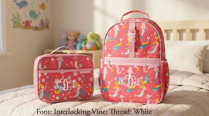 Pink Stephen Joseph mermaid backpack and lunchbox set with white "M.D.L." monogram, featuring colorful mermaid and seahorse print