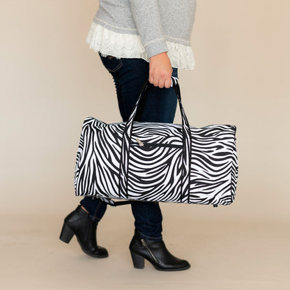 Woman carrying a zebra-print duffel by its handles