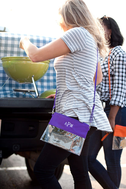 Purple and clear crossbody purse with white APM monogram worn by a woman