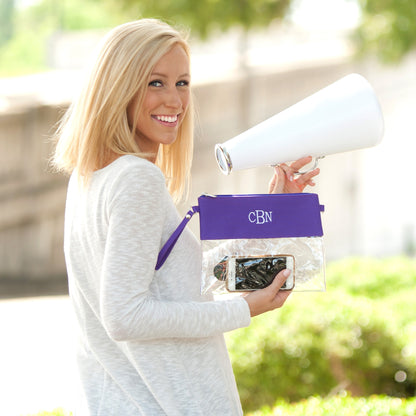 Woman holding a clear crossbody purse with a purple top flap featuring the monogram CBN.
