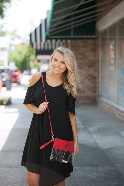 Clear bag with red trim, worn as a crossbody bag outdoors