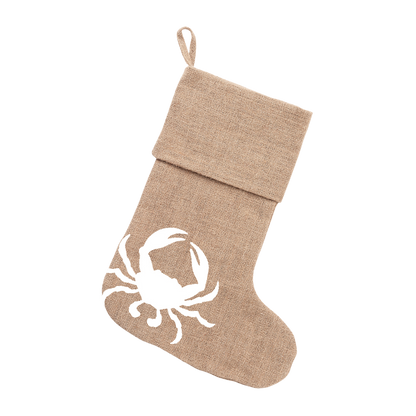 Natural burlap Christmas stocking with white crab design hanging against white shutters
