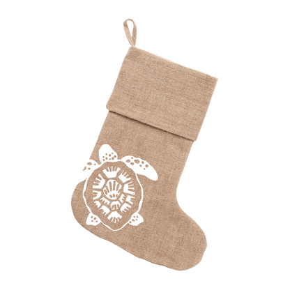 Natural burlap Christmas stocking with folded cuff and white sea turtle design hanging from its loop