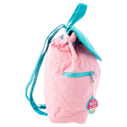 Pink quilted backpack with turquoise drawstring straps and zipper, featuring a "Wild at Heart" mushroom charm tag hanging from the front pocket