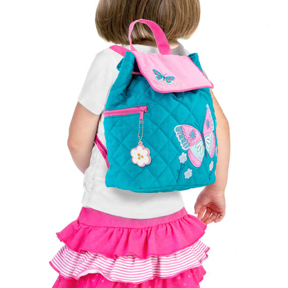 Toddler wearing teal quilted Stephen Joseph butterfly backpack with pink embroidered butterfly, floral details, and flower charm zipper pull
