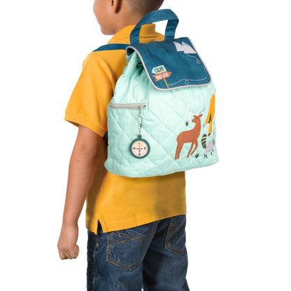 Toddler wears quilted mint and teal Stephen Joseph Outdoors backpack with embroidered deer, trees, compass charm, and "GONE WILDLING" patch on front pocket