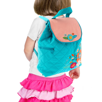 Toddler wearing turquoise quilted Stephen Joseph backpack with pink flap and colorful floral embroidery on back, shown from behind