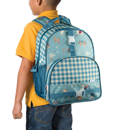 Child wearing Stephen Joseph Western Cowboy backpack with blue gingham print, horse and lasso patterns, white buckles, and mesh side pockets