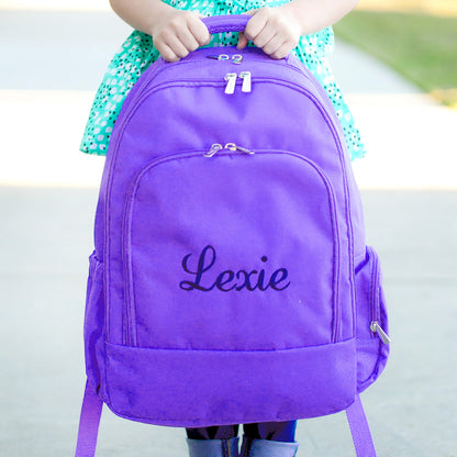 Child holding a purple backpack embroidered with Lexie