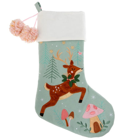Sage green stocking with a leaping brown reindeer, trees, and mushrooms, featuring a white cuff and pink pom-poms.