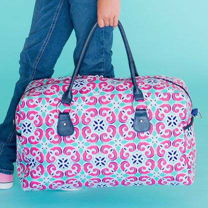 Mia tile-print duffel with dark handles carried by hand