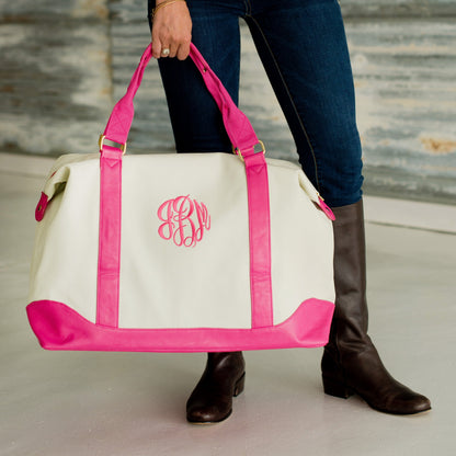 Cream weekender with pink trim and monogram carried by hand