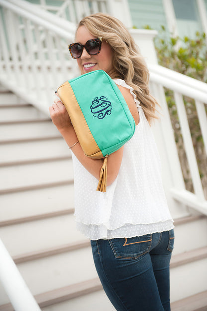 Woman holding a mint Cabana cosmetic bag near the shoulder