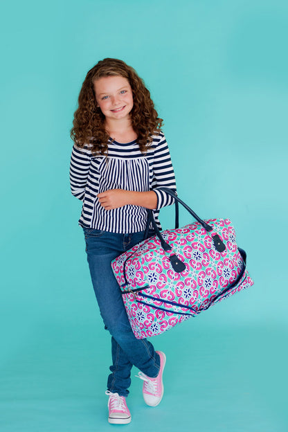Child holding a Mia tile-print duffel in front of the body