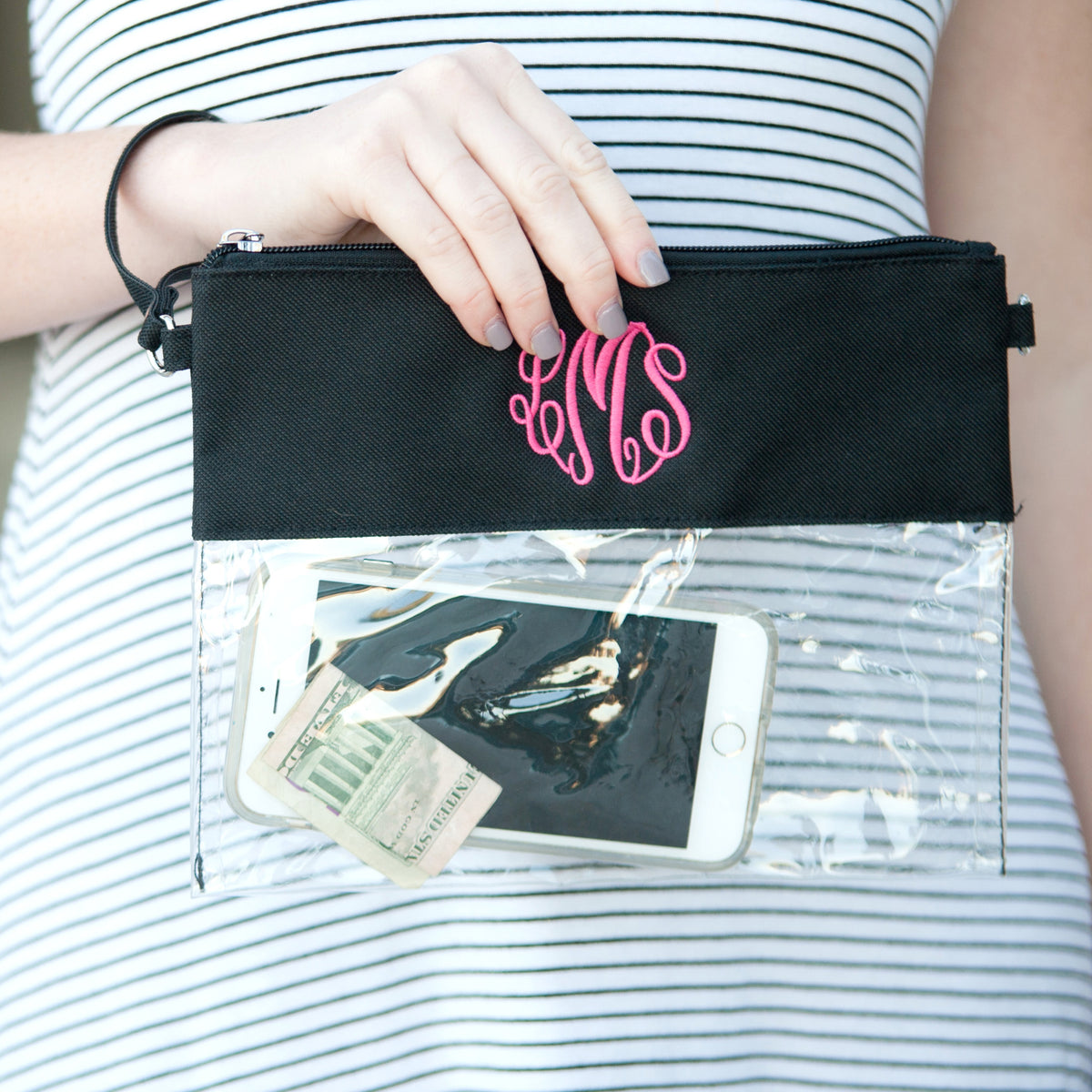 Clear bag with black trim, monogram close-up held in one hand