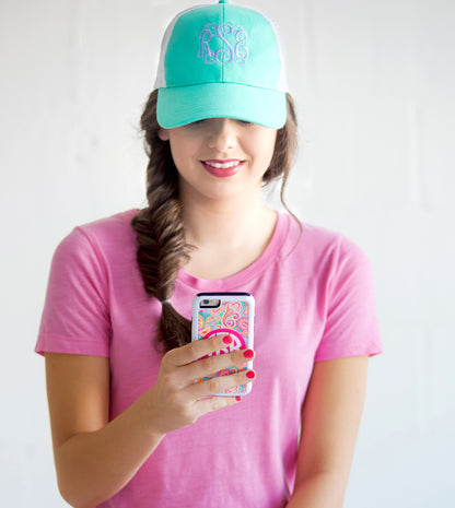 Woman wearing a mint trucker hat while looking at a phone