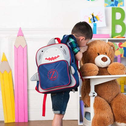 Child wearing a personalized shark backpack beside a teddy bear