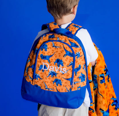 Child wearing an orange dinosaur-print backpack embroidered with Davis