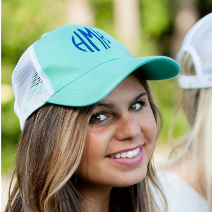 Close-up of a mint trucker hat with blue initials and white mesh back