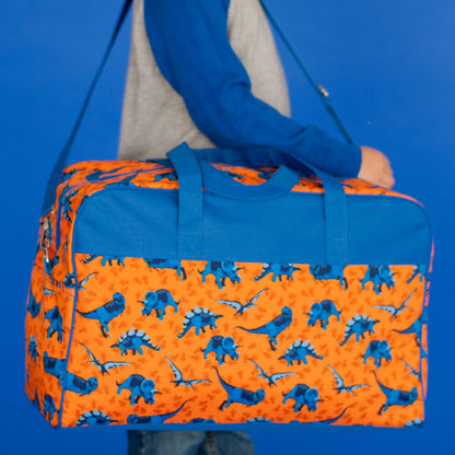 Orange dinosaur-print travel bag held by its blue handles