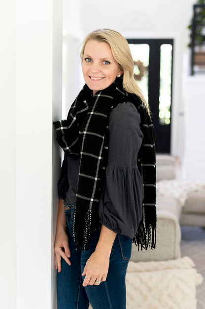 Woman wearing a black and white plaid scarf with fringe.