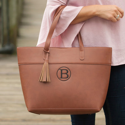 Camel Aubrey tote with a monogram and tassel held at the waist