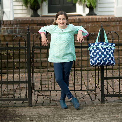 Child holding a navy llama tote outdoors
