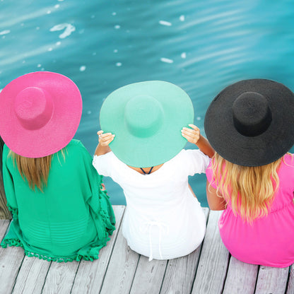 Overhead view of pink, mint and black floppy hats beside water