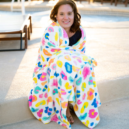 Woman wrapped in a bright multicolor leopard-print blanket