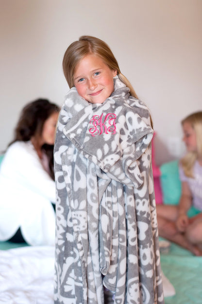 Child wrapped in a gray patterned blanket with pink personalization