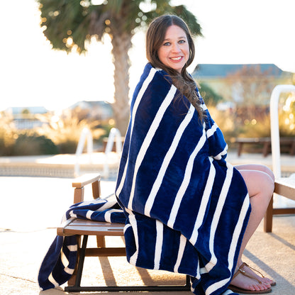 Woman seated outdoors wrapped in a navy and white striped blanket