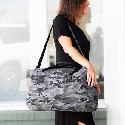 Woman carrying a gray camouflage duffel over the shoulder