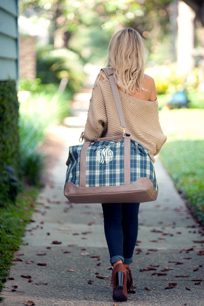 Woman carrying a plaid weekender over the shoulder outdoors