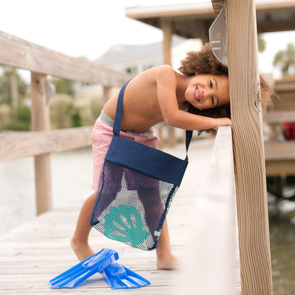 Child carrying a navy mesh tote with beach toys
