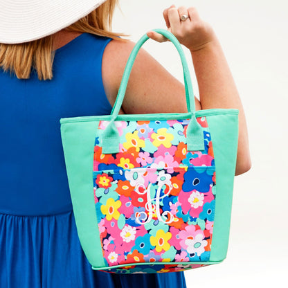 Mint cooler tote with colorful floral panel and a white monogram held by a woman