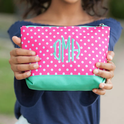 Child holding a pink polka-dot accessory pouch with mint base