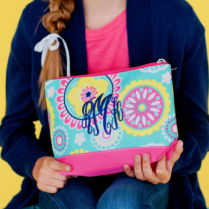 Child holding a colorful floral accessory pouch with a navy monogram