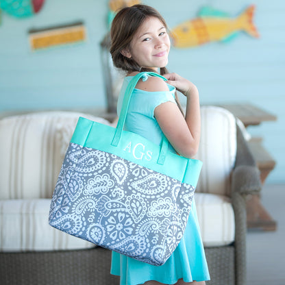 Child carrying a gray paisley tote with mint top panel