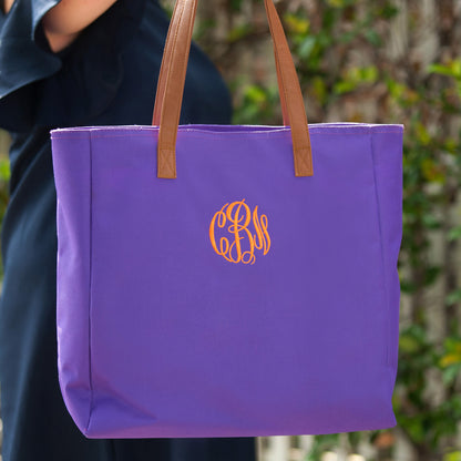 Purple tote with tan handles and gold-colored monogram