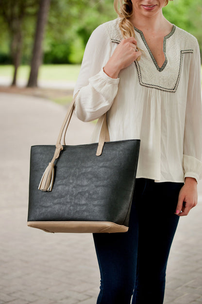 Woman carrying a black Aubrey tote with a contrasting tassel
