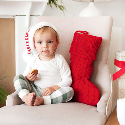 Red cable knit stocking beside a child seated in a chair