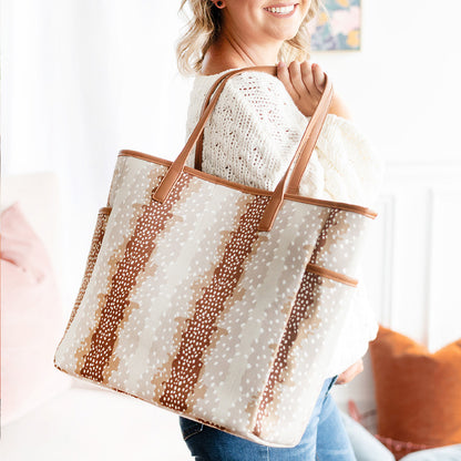Woman holding a tan spotted tote with contrasting handles