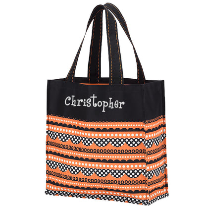 Orange black and white striped pattern tote with polka dot and scallop bands and black top panel, three quarter view on white