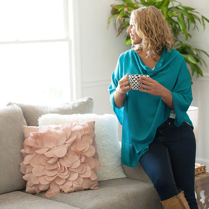 Woman seated indoors in a teal Chelsea poncho
