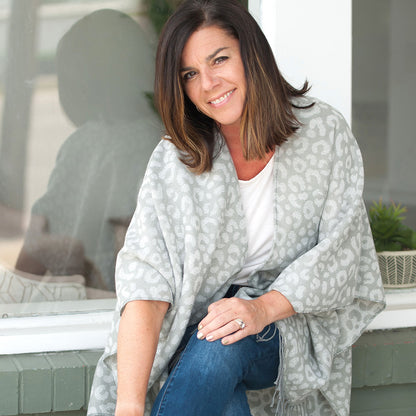 Woman seated in a light gray animal-print shawl