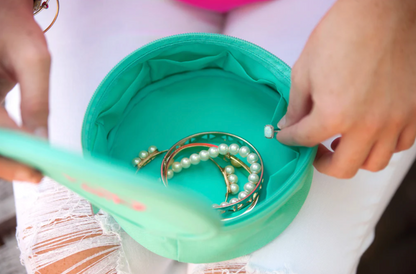 Open mint jewelry case showing fabric pockets and bracelets
